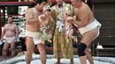 Selama "Lomba Bayi Menangis", para  pegulat sumo menggendong bayi di samping seorang wasit yang memakai kostum tradisional, Jepang, (21/9/14). (AFP PHOTO/ Yoshikazu TSUNO)