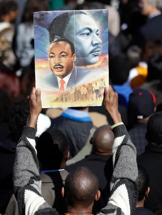 Seorang pria memegang poster Martin Luther King Jr saat menghadiri peringantan 50 tahun pembunuhan Martin Luther King Jr di Memphis, Tennessee (4/4). (AP/Mark Humprey)
