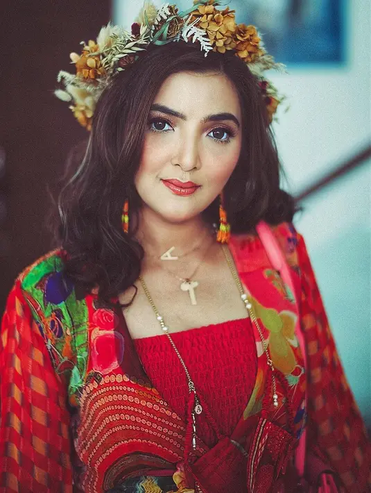 Saat liburan ke berbagai wilayah di Indonesia, ibu sambung Aurel dan Azriel ini sempat menjajal kain berwarna merah lengkap dengan mahkota bunga di kepalanya. (Liputan6.com/IG/@ananghijau)
