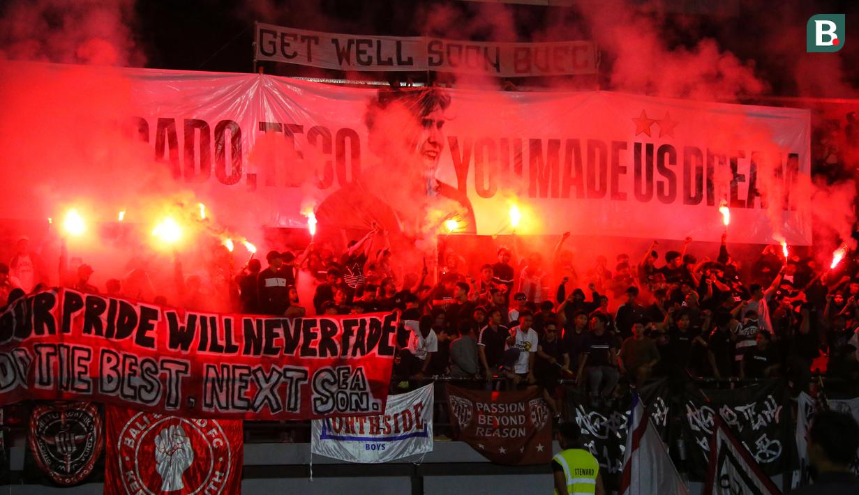 Suporter membentangkan spanduk bertuliskan "Obrigado Teco, You Made Us Dream" dengan menyalakan flare di Stadion Kapten I Wayan Dipta usai pertandingan menghadapi Madura United. (Bola.com/Alit Binawan)