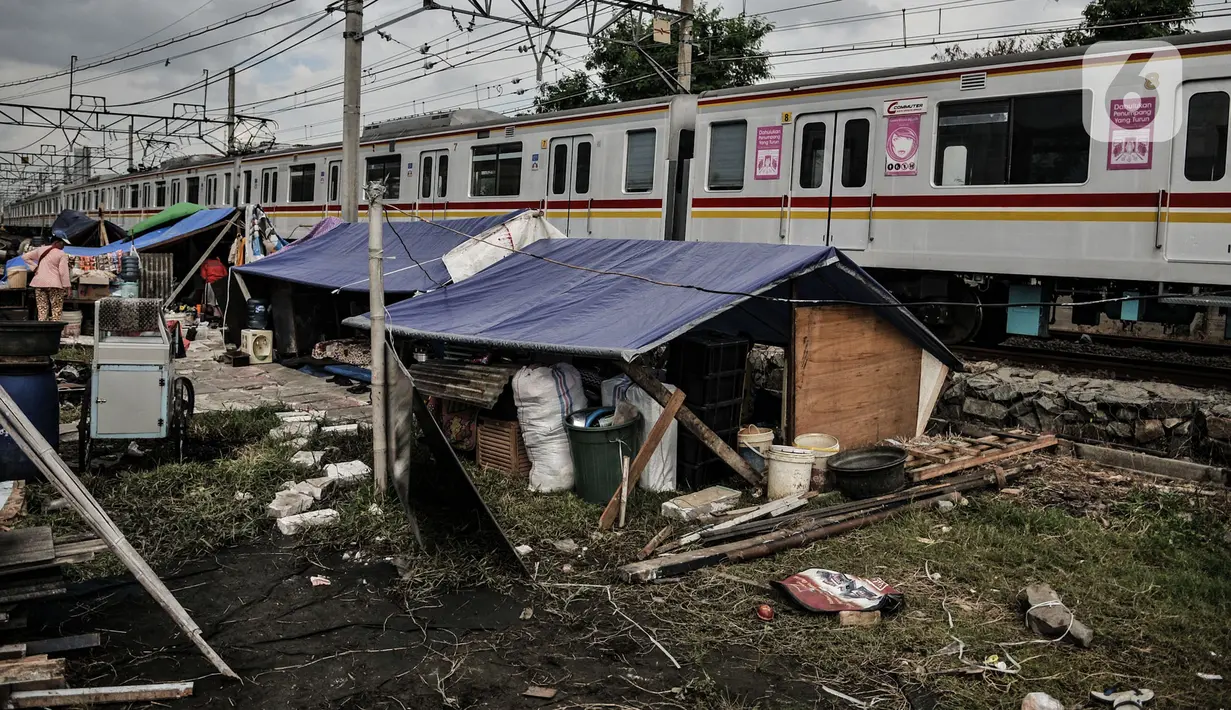 KRL melintasi tenda pengungsian korban penggusuran di tenda pengungsian RT 006/004, Kampung Bandan, Ancol, Jakarta, Kamis (16/7/2020). Korban penggusuran hanya mengandalkan tenda dari terpal dan alas triplek untuk tidur. (merdeka.com/Iqbal S. Nugroho)
