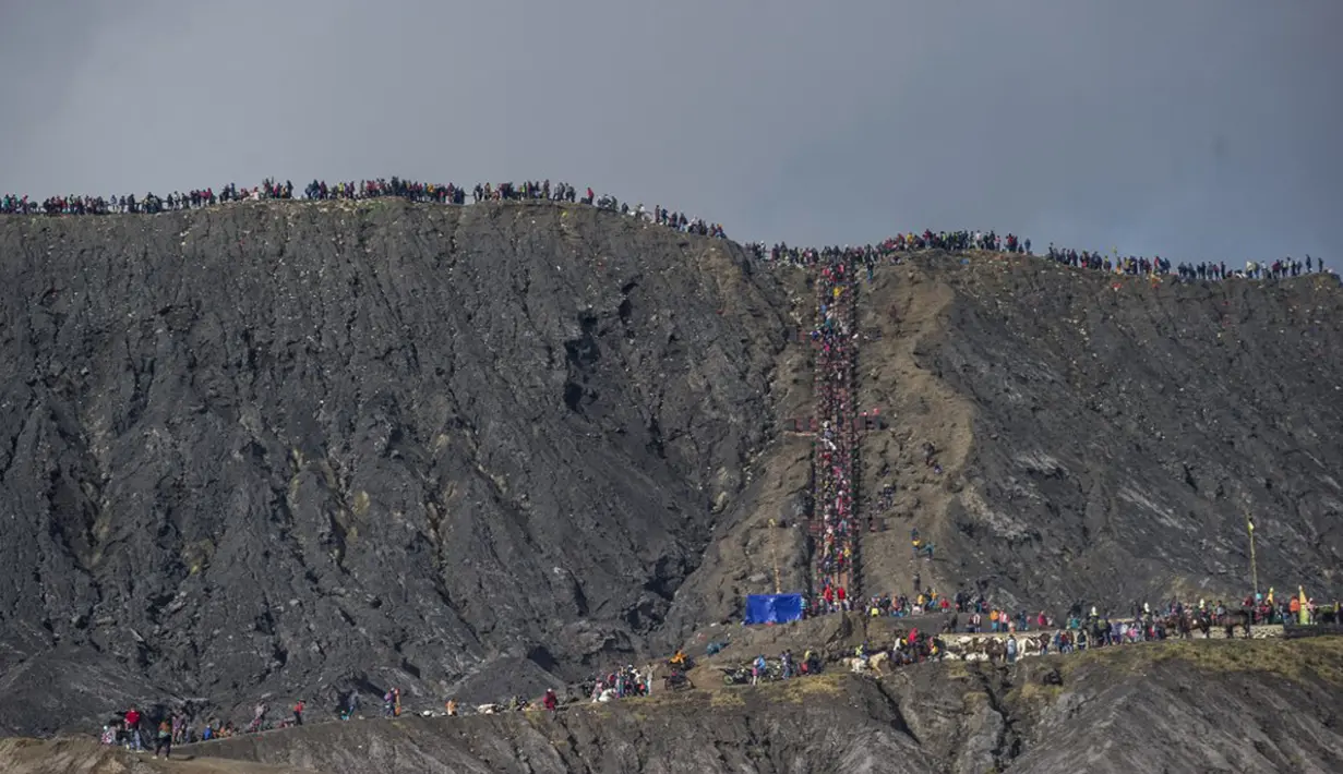 Suku Tengger berjalan ke puncak Gunung Bromo untuk melarung sesajen ke kawah saat upacara Yadnya Kasada di Probolinggo, Jawa Timur, Sabtu (26/6/2021). Suku Tengger mempersembahkan sesajen berupa beras, buah, ternak, dan barang lainnya untuk mencari berkah dari dewa. (Juni Kriswanto/AFP)