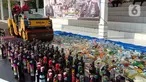 Petugas dengan alat berat menghancurkan botol minuman keras (miras) saat pemusnahan Miras dan barang bukti narkotika di Mapolrestabes Semarang, Jumat (20/12/2019). Pemusnahan barang bukti narkoba berupa sabu, inex dan pil koplo serta 5450 botol dan 140 liter ciu. (Liputan6.com/Gholib)