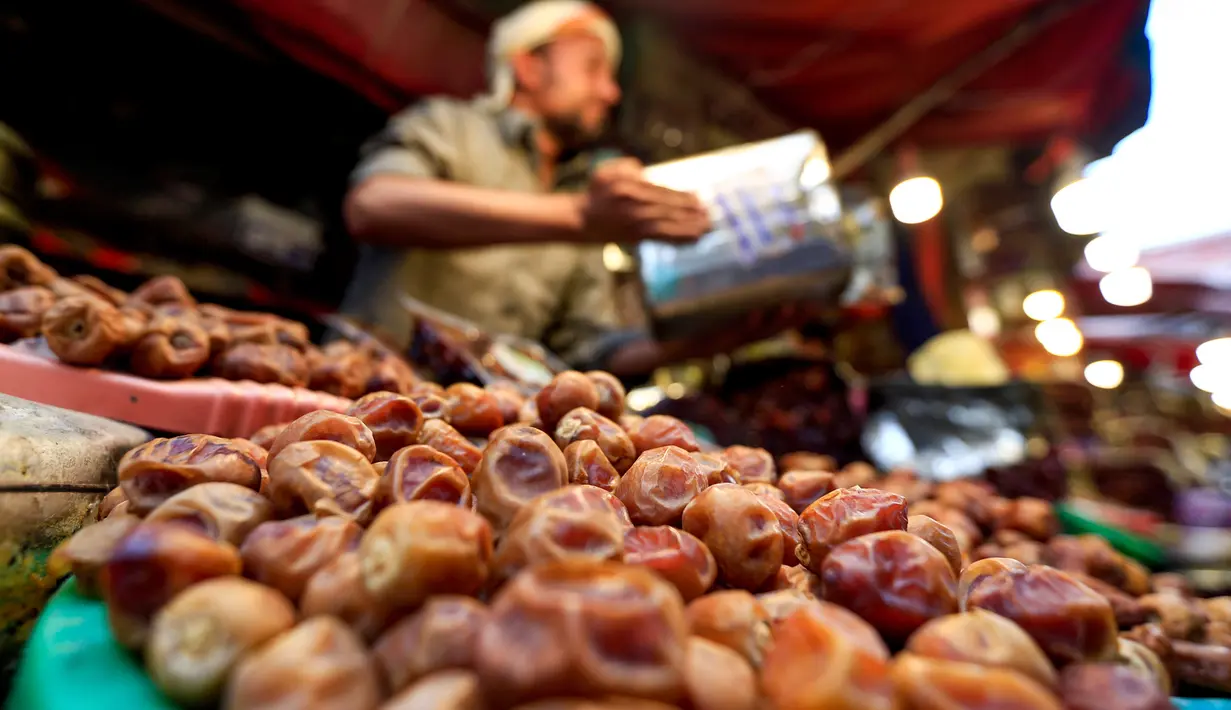 Seorang pedagang Yaman memperlihatkan kurma kering di sebuah pasar di kota tua Sanaa, Sabtu (11/5/2019). Buah kurma sangat identik saat bulan suci Ramadan, malah menjadi makanan wajib saat berbuka puasa. (Photo by Mohammed HUWAIS / AFP)
