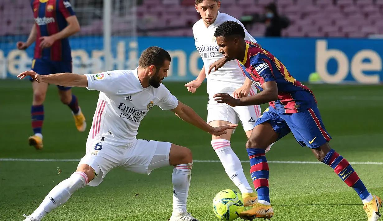 Gelandang Barccelona, Ansu Fati, berebut bola dengan bek Real Madrid, Nacho Fernandez, pada laga lanjutan Liga Spanyol di Camp Nou Stadion, Sabtu (24/10/2020) malam WIB. Real Madrid menang 3-1 atas Barcelona. (AFP/Lluis Gene)