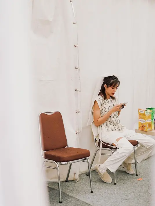Sambil menunggu waktunya manggung, Widi Vierratale, memilih untuk menghabiskan waktu dengan gadgetnya. (Foto: Instagram/@widikidiwdkdw)