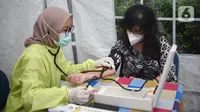 Petugas medis mengukur tekanan darah ke dokter di Puskesmas Cengkareng, Jakarta Barat, Selasa (9/2/2021). Vaksinasi Sinovac yang dilakukan secara paralel untuk tenaga kesehatan di atas 60 tahun dilakukan karena mereka rentan tertular virus Covid-19. (Liputan6.com/Fery Pradolo)