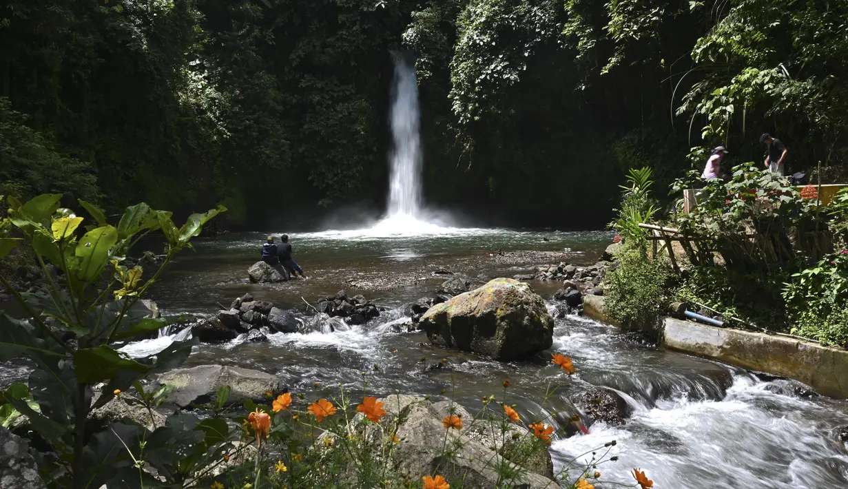Orang-orang mengunjungi Air Terjun Sengkuang, salah satu tempat wisata di Kepahiang, Provinsi Bengkulu pada 1 Mei 2021. Air Terjun Sengkuang masih sangat indah, asri serta suasana lokasi tersebut masih sunyi dan cocok untuk pengunjung yang ingin mencari ketenangan. (ADEK BERRY / AFP)
