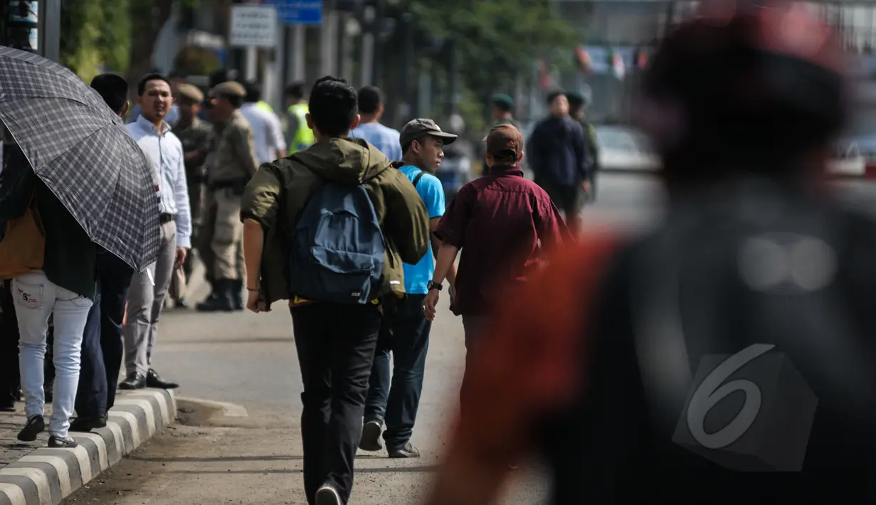 Sejumlah karyawan berjalan kaki untuk menuju kantornya di sekitar kawasan Bundaran HI, Jakarta, Rabu (22/4/2015). Sejumlah jalan utama di Jakarta ditutup total untuk sementara waktu terkait puncak Konferensi Asia-Afrika (KAA). (Liputan6.com/Faizal Fanani)