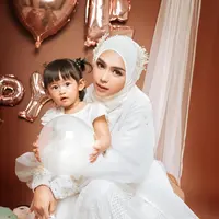 Ria Ricis sedang santer dibicarakan, lantaran dirinya ternyata telah melayangkan gugatan cerai kepada sang suami. Ria Ricis dikenal dengan gaya kompaknya bersama sang putri, Cut Raifa Aramoana atau yang akrab dipanggil Moana. Di foto ini, Ricis dan Moana tampil kompak dengan outfit serba putih. Ricis tampil cantik dengan dress putih yang memiliki detail outer yang tak kalah cantik, hijab, dan headpieces yang mempercantik penampilannya secara keseluruhan. Di pangkuannya, Moana juga mengenakan dress putih lengan pendek dengan rambut yang dikuncir dua menggemaskan. [Foto: Instagram/riaricis1795]