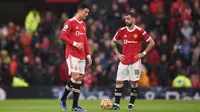 Striker Manchester United Cristiano Ronaldo dan gelandang Bruno Fernandes bereaksi dalam laga Liga Inggris melawan Manchester City di Old Trafford, Sabtu, 6 November 2021. (Oli SCARFF / AFP)