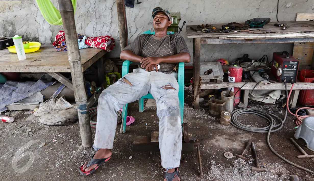 Seorang warga tengah tertidur lelap di bengkel las di kawasan Kampung Nelayan Cilincing, Jakarta Utara, Rabu (8/2). (Fery Pradolo/Liputan6.com)