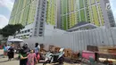 Warga berjalan dekat proyek Rusunawa Pasar Rumput yang hampir selesai pengerjaannya di Jakarta, Selasa (16/7/2019). Rusunawa Pasar Rumput akan diresmikan oleh Presiden Joko Widodo atau Jokowi pada Agustus mendatang. (Liputan6.com/Immanuel Antonius)