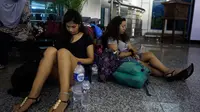 Calon penumpang menunggu di Bandara Ngurah Rai setelah pihak maskapai membatalkan penerbangan di Bali, Kamis (28/6). PT Angkasa Pura I menutup sementara operasional bandara selama 16 jam dikarenakan dampak abu vulkanik Gunung Agung. (AP/Firdia Lisnawati)