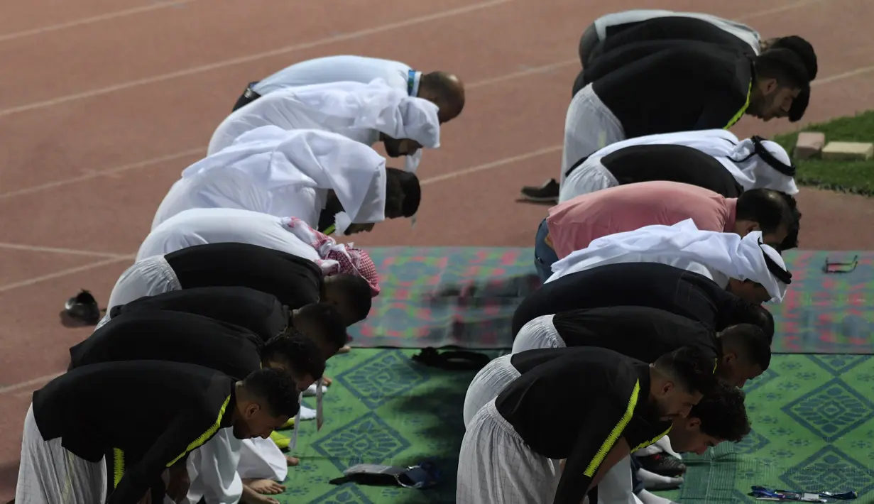 Para pemain Timas Qatar salat berjamaah sebelum sesi latihan mereka di Abu Dhabi (31/1). Qatar harus melewati Korea Selatan sebelum menginjakkan kakinya di final Piala Asia 2019. (AFP Photo/Roslan Rahman)