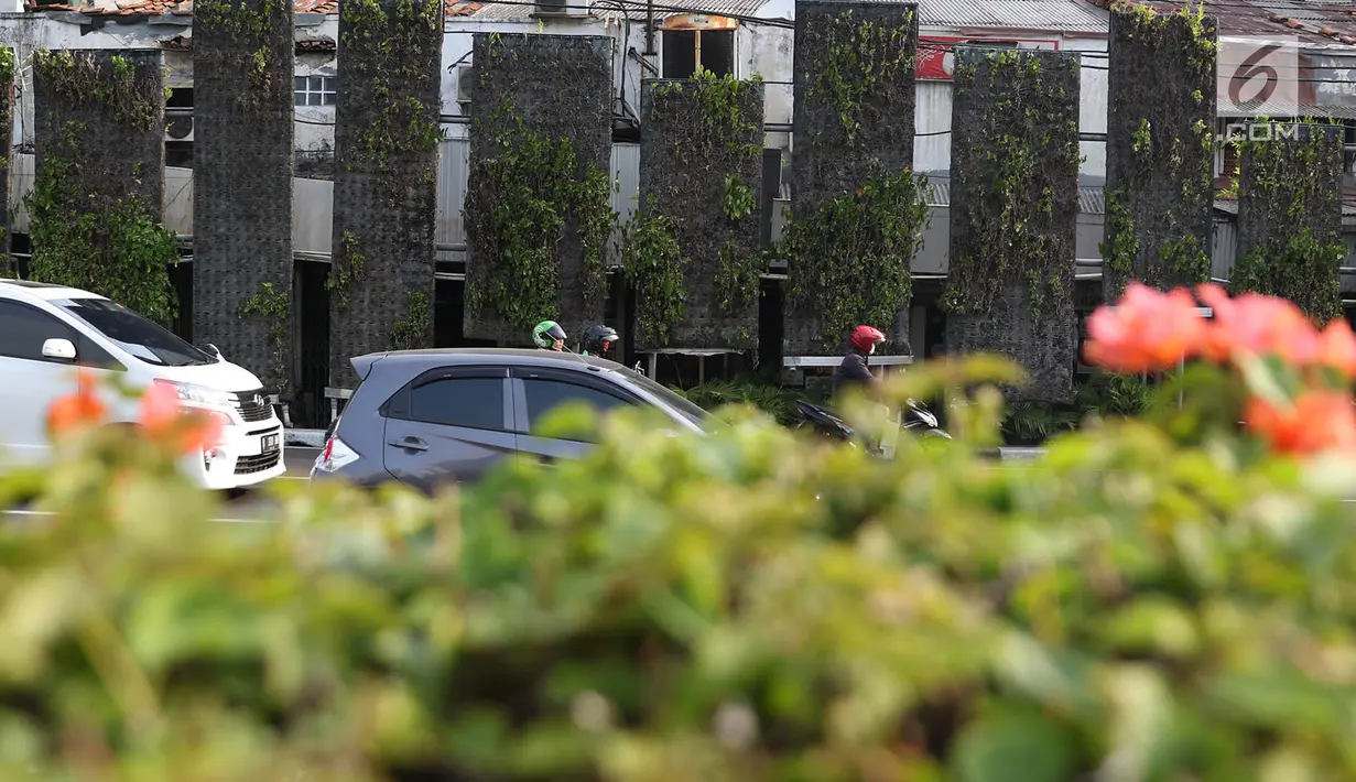Kendaraan melintas di depan taman vertikal kawasan Tugu Tani, Jakarta Pusat, Senin (17/7). Tanaman hias yang dulu yang berjajar indah dan asri, kini banyak yang mati sehingga mengganggu keindahan kota. (Liputan6.com/Immanuel Antonius)