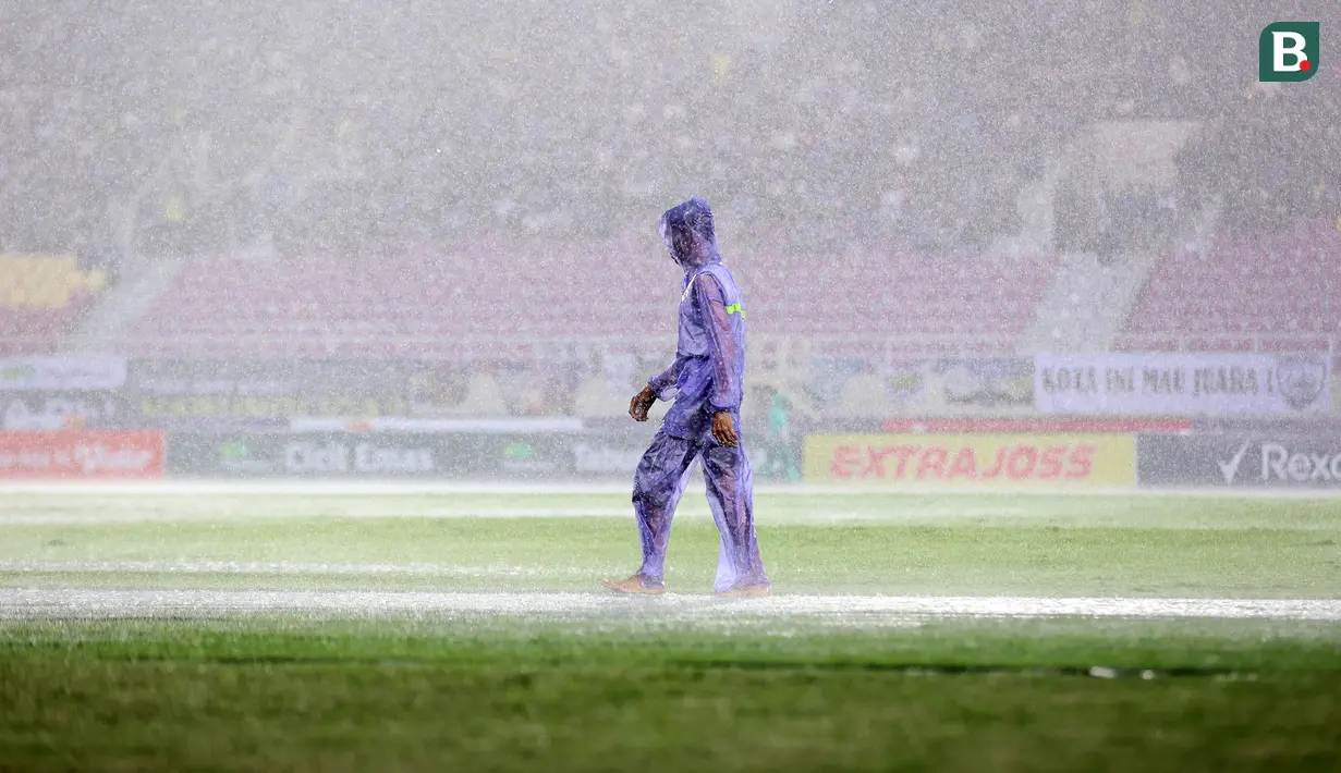 Seorang petugas sedang mengecek lapangan pertandingan di bawah guyuran hujan dalam laga final Pegadaian Liga 2 2024/2025 antara Bhayangkara FC melawan PSIM Yogyakarta di Stadion Manahan, Solo, Jawa Tengah, Rabu (26/02/2025). (Bola.com/Abdul Aziz)