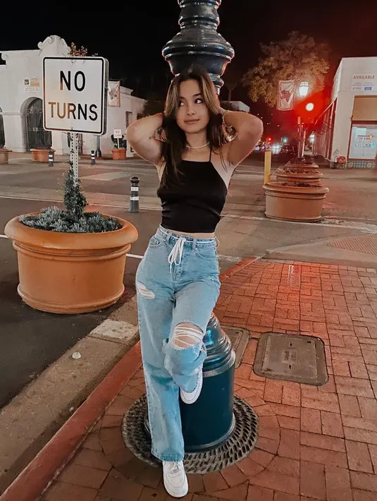 Effortlessly chic, Caitlin tampil dengan halter crop top dan ripped jeans serta sneakers. [IG: caitlinhalderman].