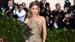 Model Gigi Hadid berpose saat menghadiri Met Gala 2018 di Metropolitan Museum of Art, New York (7/5). Gigi tampil cantik mati mengenakan gaun asimetris beraneka warna dengan kain tipis berkilauan, milik Versace. (AP Photo/Charles Sykes)