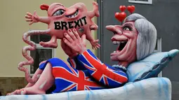 Kereta karnaval membawa karikatur yang menggambarkan Perdana Menteri Inggris, Theresa May melahirkan bayi Brexit-nya dalam parade karnaval Rose Monday di Duesseldorf, Jerman, Senin (12/2). (AP Photo/Martin Meissner)