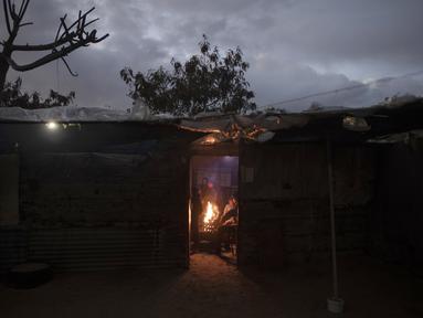 Sebuah keluarga Palestina menghangatkan diri di dekat api saat cuaca dingin di daerah kumuh di pinggiran kamp pengungsi Khan Younis, Jalur Gaza selatan pada Rabu, 19 Januari 2022. (AP Photo/Khalil Hamra)