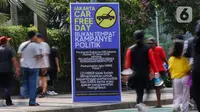 Warga berolahraga di dekat poster peringatan larangan kampanye politik saat Hari Bebas Kendaraan Bermotor atau Car Free Day (CFD) di Kawasan Bundaran HI, Jakarta, Minggu (19/11/2023). (Liputan6.com/Angga Yuniar)