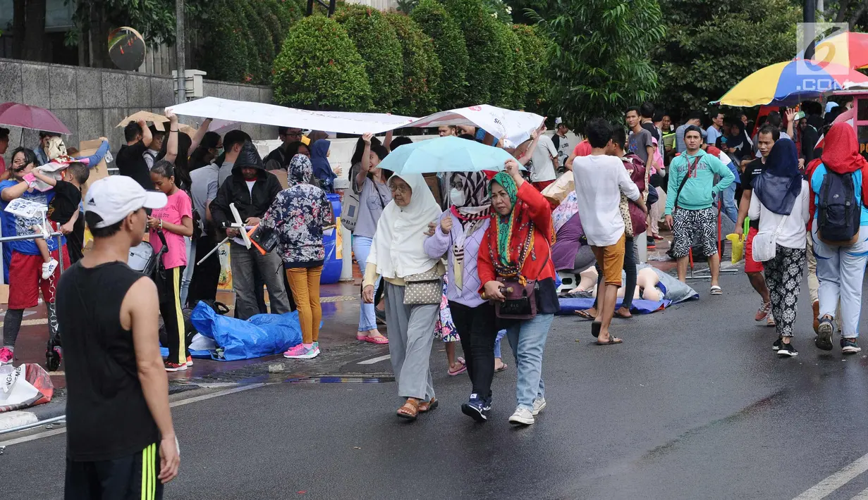 Warga berlindung dari hujan gerimis di sekitar Bundaran Hotel Indonesia, Jakarta, Minggu (26/11). Angin kencang dan gerimis terjadi saat kegiatan Hari Bebas Kendaraan, Minggu pagi. (Liputan6.com/Helmi Fithriansyah)