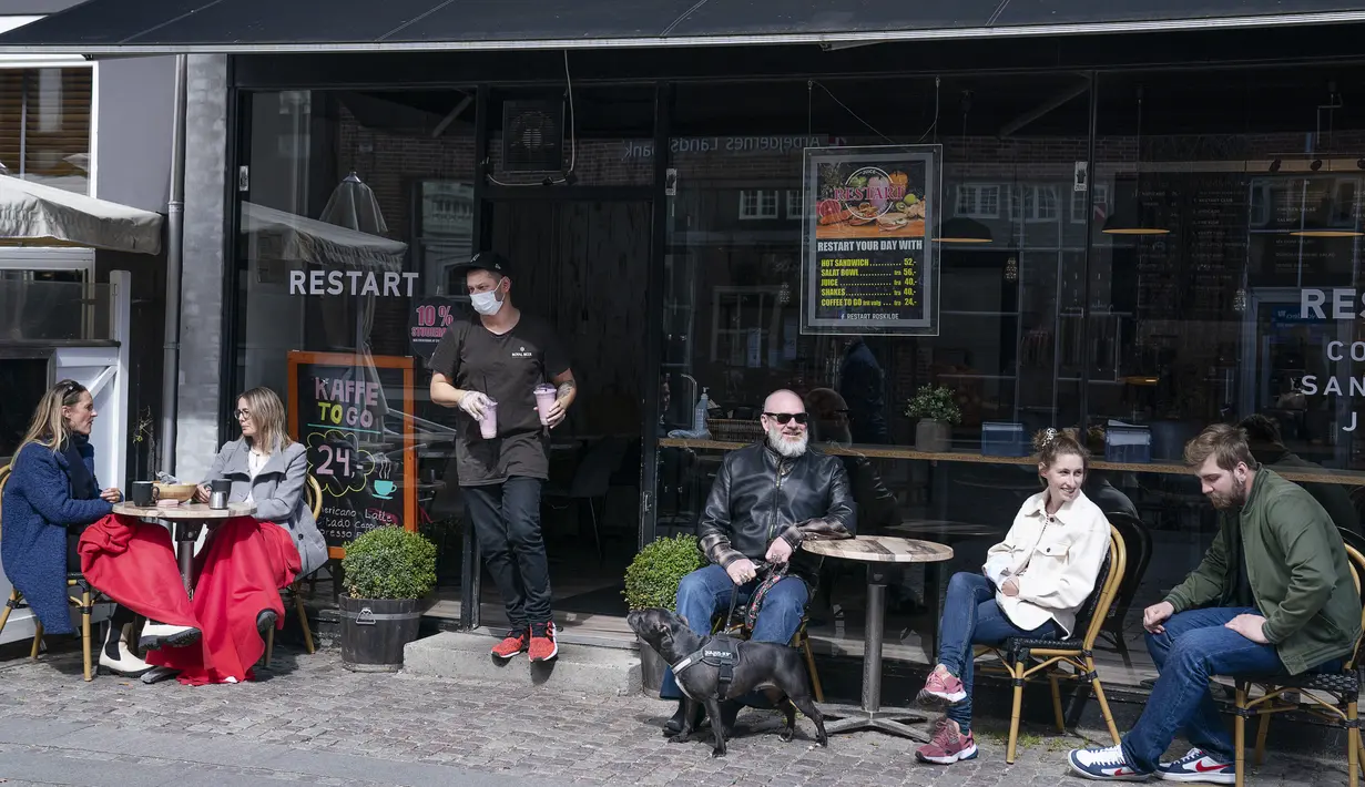 Orang-orang duduk menikmati layanan luar ruangan kafe di Roskilde Denmark, saat kafe dan bar dibuka kembali pada Rabu (21/4/2021). Denmark membuka kembali berbagai aktivitas ekonomi negaranya setelah kasus infeksi Covid-19 mengalami penurunan. (Claus Bech/Ritzau Scanpix via AP)