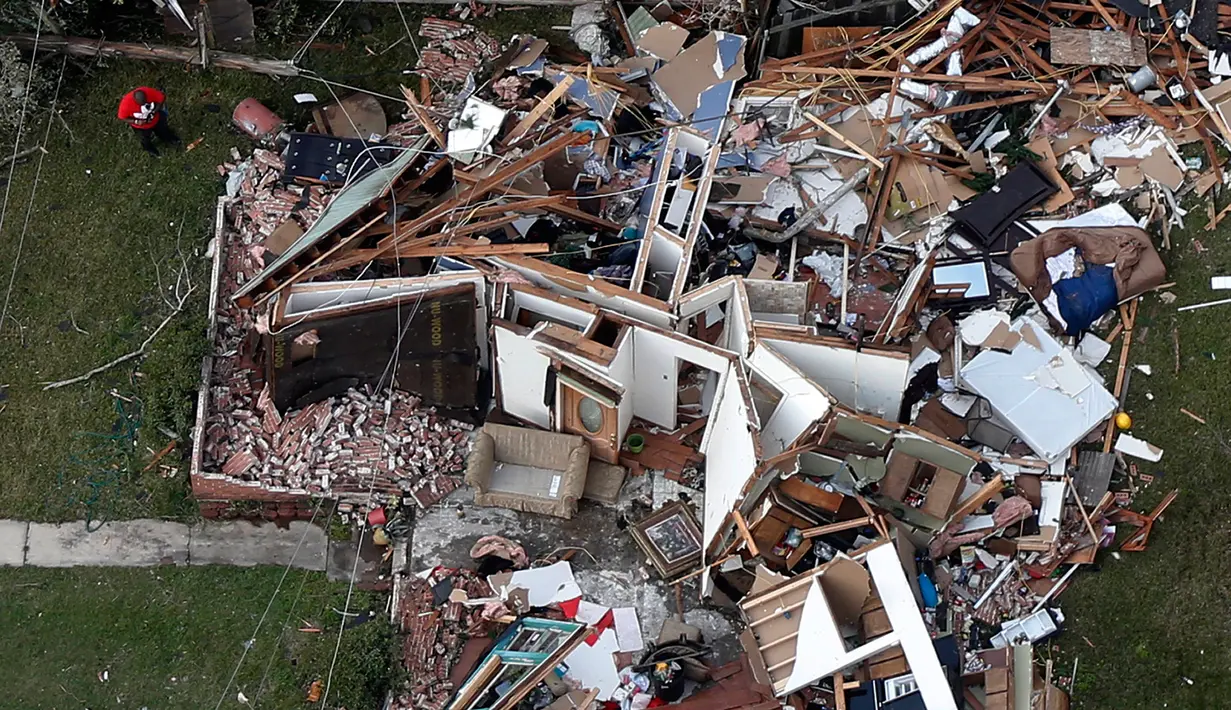 Seorang pria berdiri didekat rumah yang rusak akibat dihantam tornado di New Orleans, AS (7/2). Selain merusak banyak bangunan dan menumbangkan tiang listrik, tornado juga menerbangkan atap rumah serta menggulingkan truk makanan. (AP Photo/Gerald Herbert)