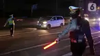 Polisi menghalau kendaraan berpenumpang di tol Jakarta-Cikampek untuk keluar ke Gerbang tol Cikarang Barat, Kab. Bekasi, Jumat (24/4/2020). Akses transportasi mobil pribadi dan bus angkutan penumpang dari tol Jakarta Cikampek menuju Karawang ditutup mulai Jumat (24/4). (Liputan6.com/Herman Zakharia)