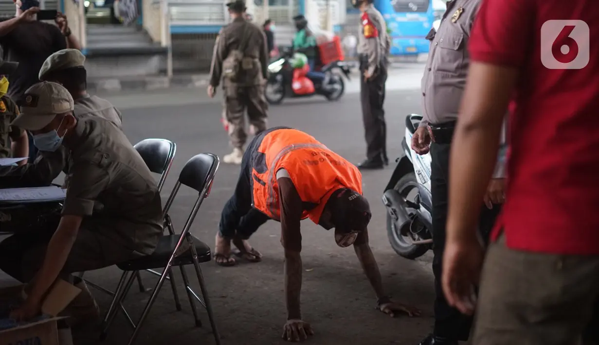 Petugas menghukum warga pelanggar Operasi Yustisi Pencegahan Covid-19 di kawasan Kampung Melayu, Jakarta Timur, Senin (16/11/2020). Operasi tersebut digelar guna menyadarkan masyarakat akan pentingnya penggunaan masker di tengah pandemi Covid-19. (Liputan6.com/Immanuel Antonius)