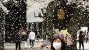 Seorang pengunjung berfoto di bawah pancuran bunga sakura yang mekar penuh di kuil shinto di Tokyo, Kamis (31/3/2022). (AP Photo/Shuji Kajiyama)