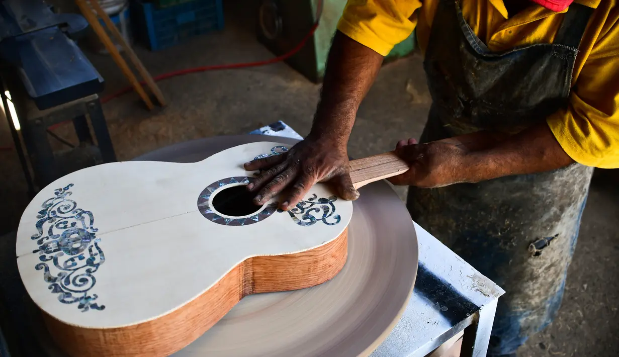 Pengrajin Salvador Meza membuat replika gitar dari film "Coco" di rumah produksinya di Paracho, Meksiko (8/1). Karena banyaknya permintaan, pengrajin ini tidak dapat memenuhi semua pesanan. (AFP Photo/ Ronaldo Schemidt)
