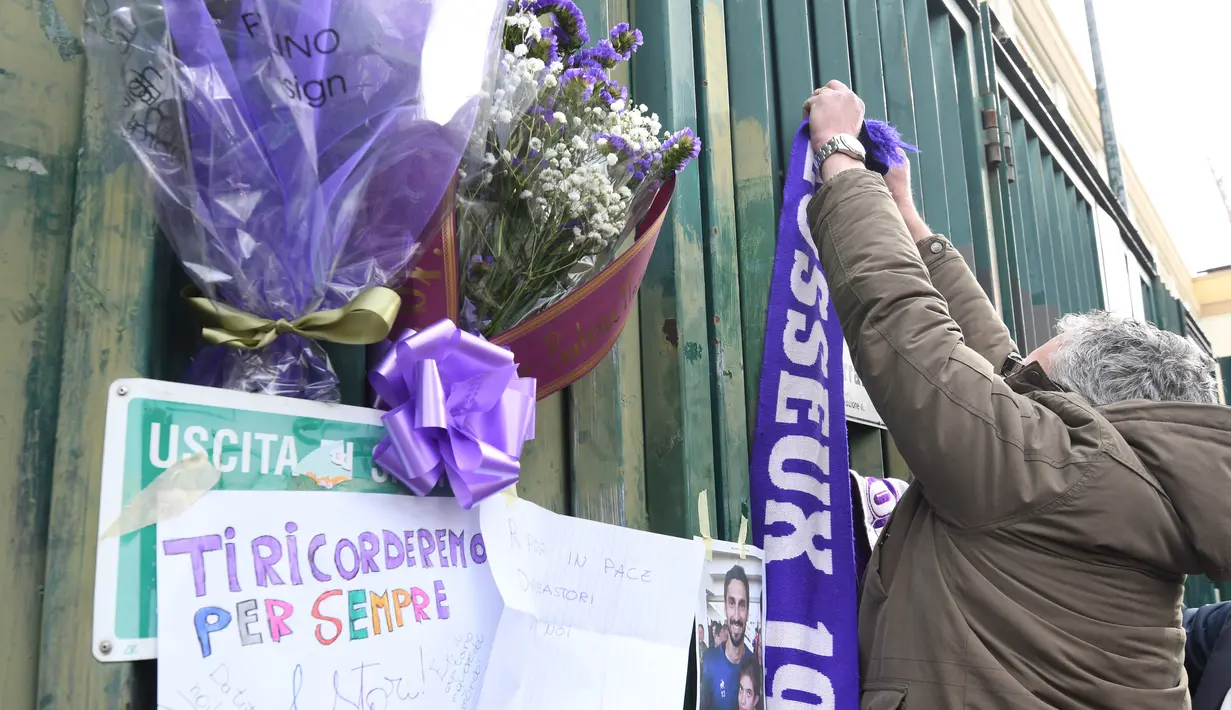 Penggemar menggantung syal ungu Fiorentina untuk mengenang Davide Astori di pagar Stadion Artemio Franchi, Florence, Minggu (4/3). Astori ditemukan meninggal oleh rekan timnya di kamar hotel jelang laga Fiorentina kontra Udinese. (Claudio GIOVANNINI/AFP)