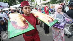 Warga membawa roti buaya saat meramaikan Festival Palang Pintu 2016 di Kemang, Jakarta, (28/5). Festival tersebut menampilkan budaya Betawi di sepanjang Jalan Kemang Raya dengan dua panggung utama dan sekitar 270 booth. (Liputan6.com/Immanuel Antonius)