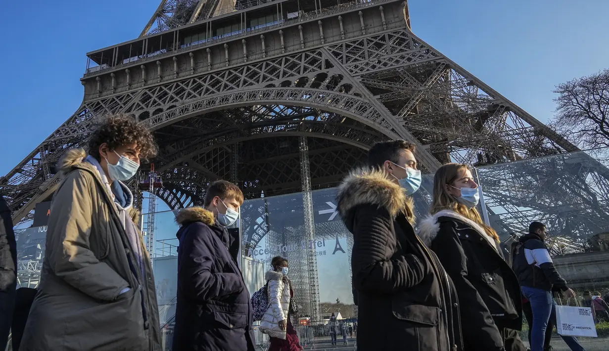 Orang-orang yang memakai masker berjalan melewati Menara Eiffel di Paris, Selasa (21/12/2021). Negara-negara di seluruh Eropa mempertimbangkan pembatasan yang lebih ketat guna membendung gelombang baru infeksi COVID-19 yang didorong oleh varian omicron yang sangat menular. (AP Photo/Michel Euler)