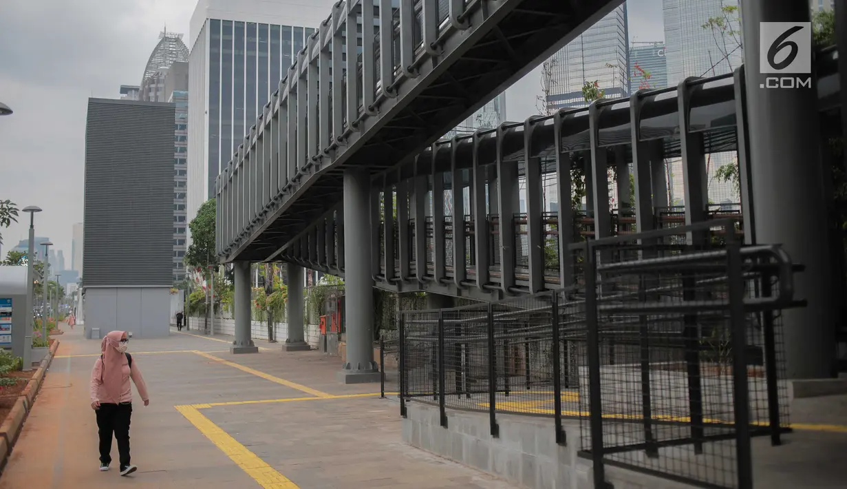 Pejalan kaki melintas di dekat JPO di Jalan Sudirman, Jakarta, Rabu (28/8/2019). Pemprov DKI Jakarta akan membangun 15 JPO berkonsep modern atau futuristik pada 2020. Tujuannya untuk memfasilitasi pejalan kaki agar nyaman mengakses transportasi publik. (Liputan6.com/Faizal Fanani)