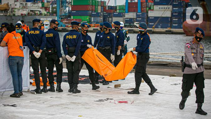 Petugas membawa body part dari kapal Basarnas di JICT II Tanjung Priok, Jakarta, Jumat (15/1/2021). Badan SAR Nasional (Basarnas) kembali menerima paket kiriman hasil pencarian hari ketujuh. (Liputan.com/Faizal Fanani)