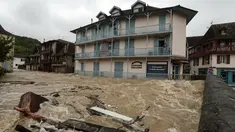Warga berdiri di balkon lantai atas sebuah gedung menyaksikan banjir merendam jalanan setelah hujan lebat di Salies-de-Bearn, Prancis barat daya (13/6). (AFP Photo/Iroz Gaizka)