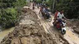 Penduduk desa melakukan perjalanan di dekat bendungan Stung Prek Tnaot setelah banjir menyusul hujan di pinggiran Phnom Penh, Kamboja (14 /10/2020). Pejabat bencana Kamboja mengatakan bahwa lebih dari 10.000 orang telah dievakuasi ke tempat aman setelah badai tropis melanda. (AP Photo/Heng Sinith)
