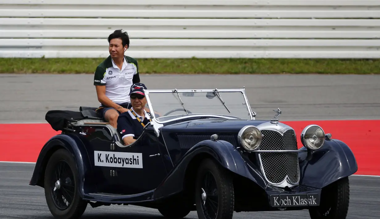 Kamui Kobayashi, pembalap Formula Satu asal Jepang ikut berparade mengelilingi Sirkuit Hockenheim menggunakan mobil antik, (20/7/2014). (REUTERS/Michael Dalder)