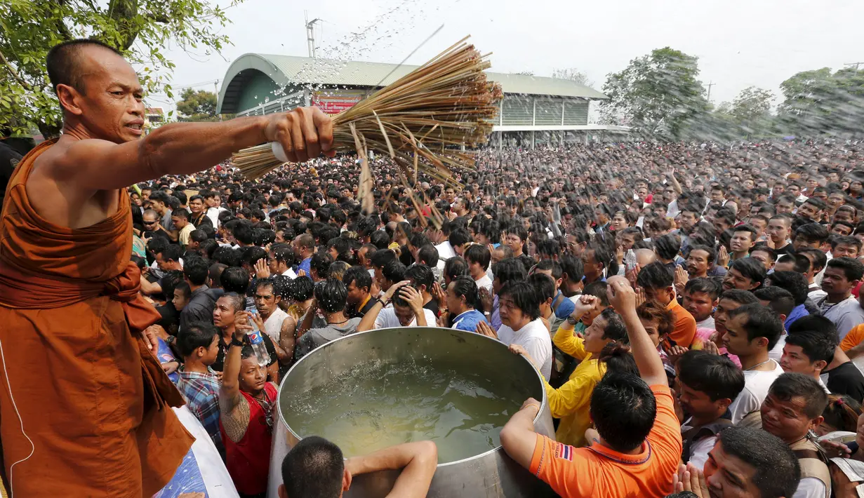 Biksu Buddha bhakta memberikan air suci kepada ribuan warga selama Festival Tato Sihir di Wat Bang Phra, Thailand (19/3). Mereka percaya tato memiliki kekuatan mistis, menangkal nasib buruk dan melindungi mereka dari bahaya. (REUTERS/Chaiwat Subprasom)