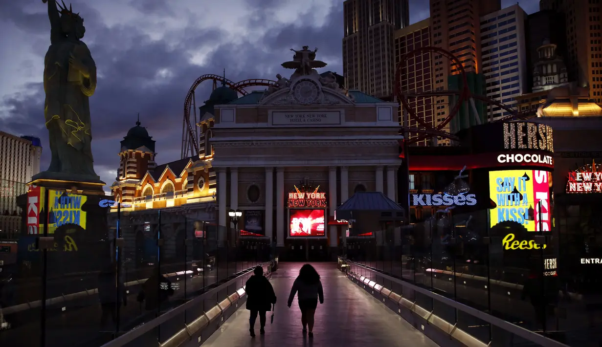 Orang-orang berjalan di sepanjang Las Vegas Strip yang sepi setelah perintah penutupan kasino akibat virus corona COVID-19, Las Vegas, Amerika Serikat, Rabu (18/3/2020). Selain kasino, bioskop, bar, restoran, dan pusat kebugaran juga ditutup. (AP Photo/John Locher)