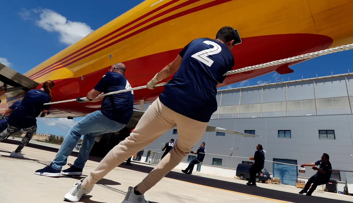 Anggota tim berusaha untuk menarik pesawat DHL Boeing 757 sejauh 20 meter di Safi Aviation Park, Malta pada 1 Mei 2019. Kegiatan tarik pesawat tersebut merupakan rangkaian dalam rangka untuk penggalangan dana amal. (REUTERS/Darrin Zammit Lupi)