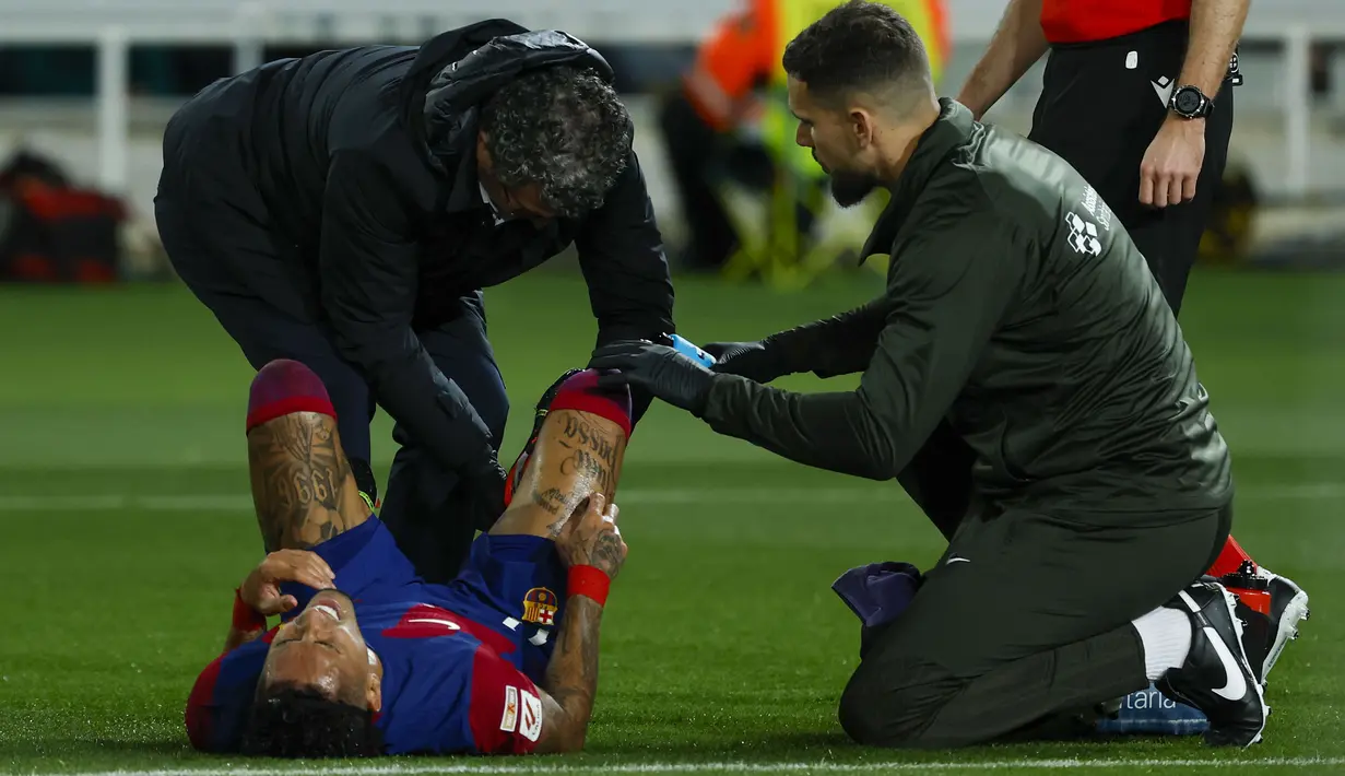 Striker Barcelona, Raphinha mendapat perawatan medis setelah mengalami cedera saat menghadapi Mallorca pada laga pekan ke-28 LaLiga 2023/2024 yang berlangsung di Olimpic Lluis Companys Stadium, Barcelona, Sabtu (9/3/2024) dini hari WIB. (AP Photo/Joan Monfort)