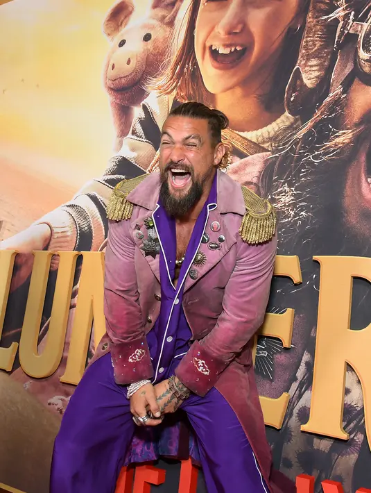 <p>Jason Momoa berpose dengan boneka babi saat menghadiri pemutaran perdana film Netflix "Slumberland" di AMC Century City di Century City, California pada 9 November 2022. Mamoa kemudian mengenakan jaket merah muda gelap yang dia kenakan dalam fitur tersebut. (Charley Gallay/Getty Images for Netflix/AFP)</p>