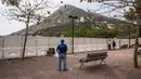 Seorang pria menyaksikan pekerja memasang pagar untuk memblokir akses ke Pantai Shek O di Hong Kong, Kamis (17/3/2022). Pemerintah Hong Kong mengatakan akan menutup pantai umum untuk mengekang penyebaran virus corona COVID-19. (DALE DE LA REY/AFP)