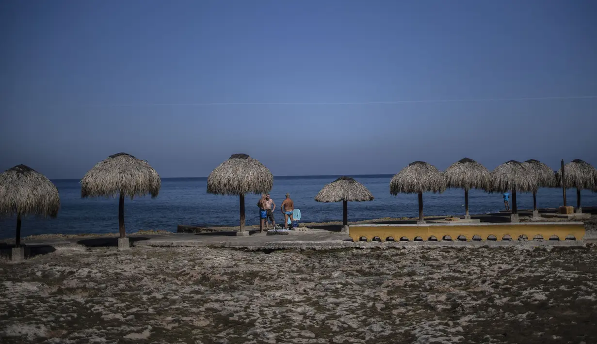 Turis berdiri di sepanjang tepi pantai di Havana, Kuba, pada 2 Maret 2021. Kepulauan Karibia memburu pengunjung untuk menggerakkan kembali roda ekonomi yang terhenti di salah satu kawasan di dunia yang sangat bergantung dengan sektor pariwisata. (AP Photo/Ramon Espinosa)