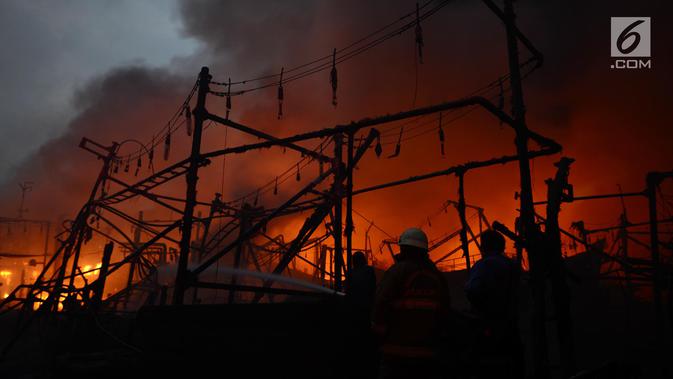 Petugas damkar berusaha menjinakan api yang membakar kapal nelayan di Pelabuhan Muara Baru, Penjaringan, Jakarta Utara, Sabtu (23/2). Sebanyak 18 kapal nelayan terbakar yang belum diketahui penyebabnya. (merdeka.com/Imam Bukhori)