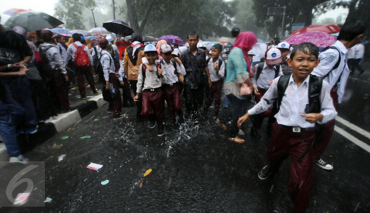 Sejumlah pelajar SD bermain hujan usai menyambut kedatangan Raja Salman di sekitar Istana Bogor, Rabu (1/3). Kedatangan Raja Salman bin Abdulaziz ke Istana Bogor disambut puluhan ribu pelajar dan warga. (Liputan6.com/Helmi Fithriansyah) 
